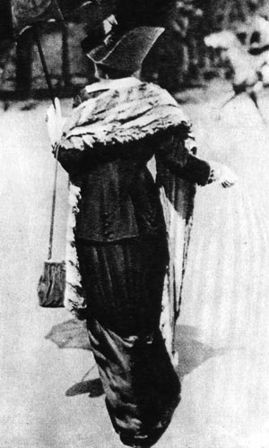 480. Фотография дамы того времени, посещающей скачки. На ней платье, состоящее из двух частей, меховая накидка, шляпа с перьями, в руках сумочка и зонтик. 